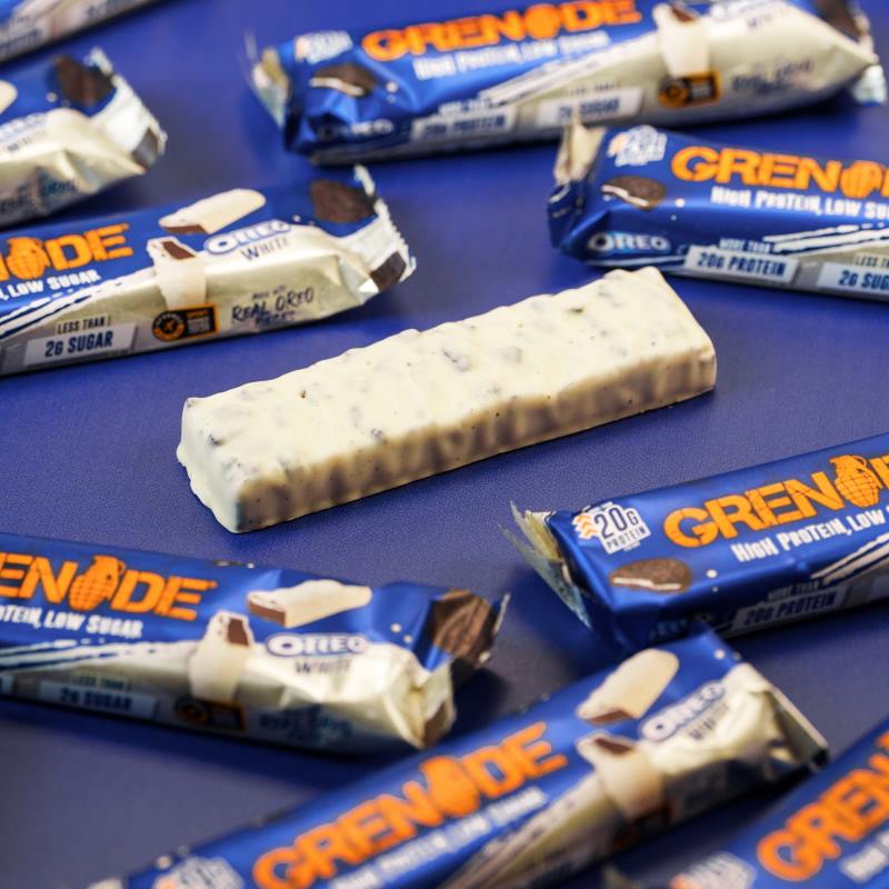 Ein einzelner Grenade Proteinriegel Oreo White ohne Verpackung, auf einem Tisch liegend, mit weißer Schokolade überzogen.