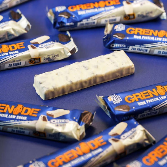 Ein einzelner Grenade Proteinriegel Oreo White ohne Verpackung, auf einem Tisch liegend, mit weißer Schokolade überzogen.