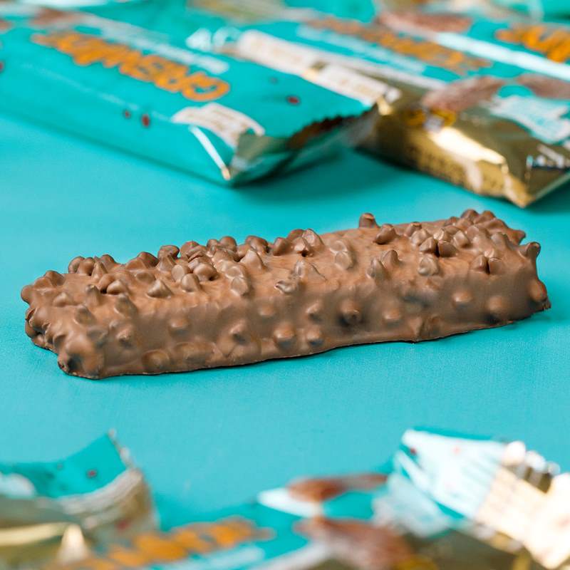 Ein einzelner Grenade Protein Riegel Chocolate Chip Salted Caramel liegt ohne Verpackung auf einem Tisch.