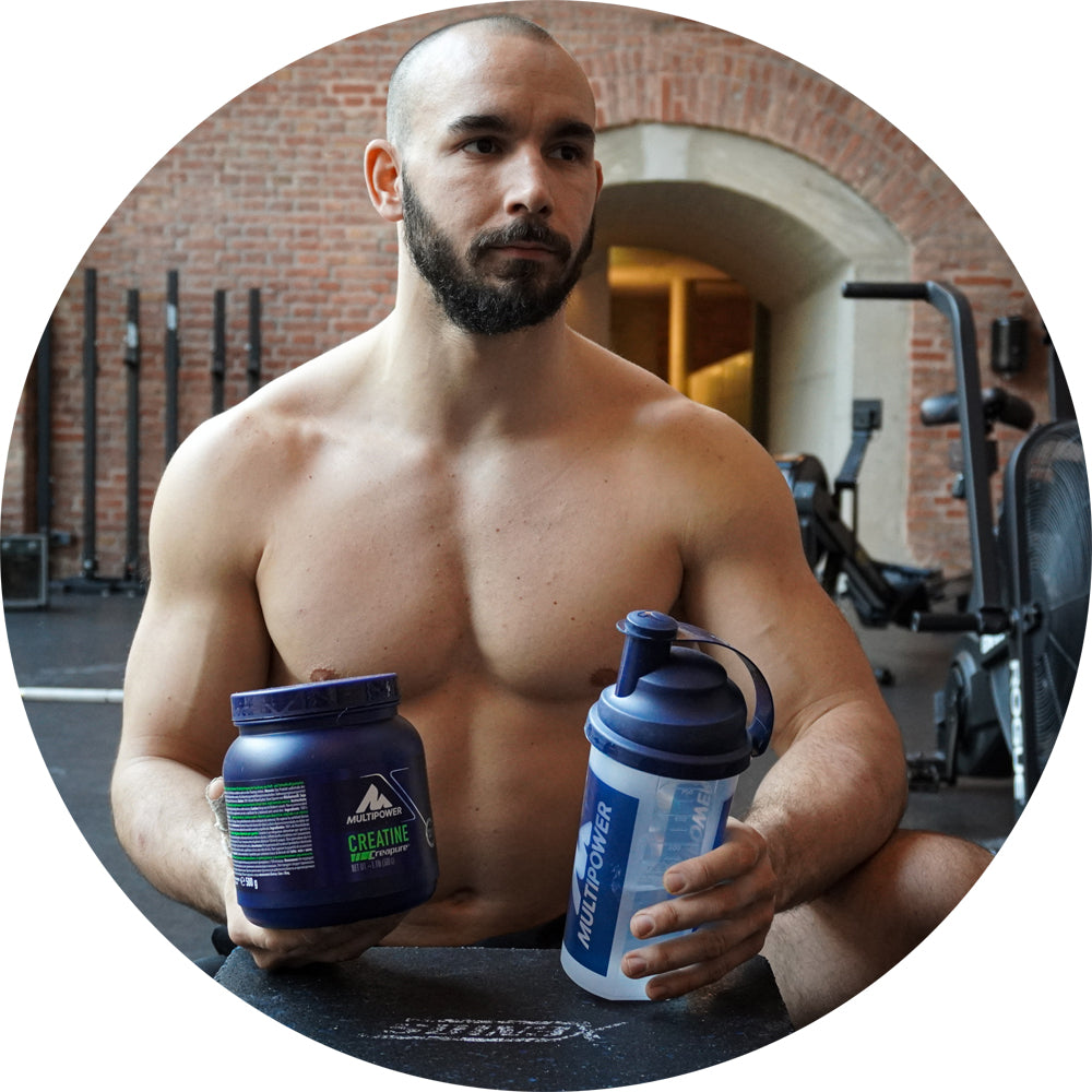 Kraftsportler mit Creatin und Protein Shaker in der Hand