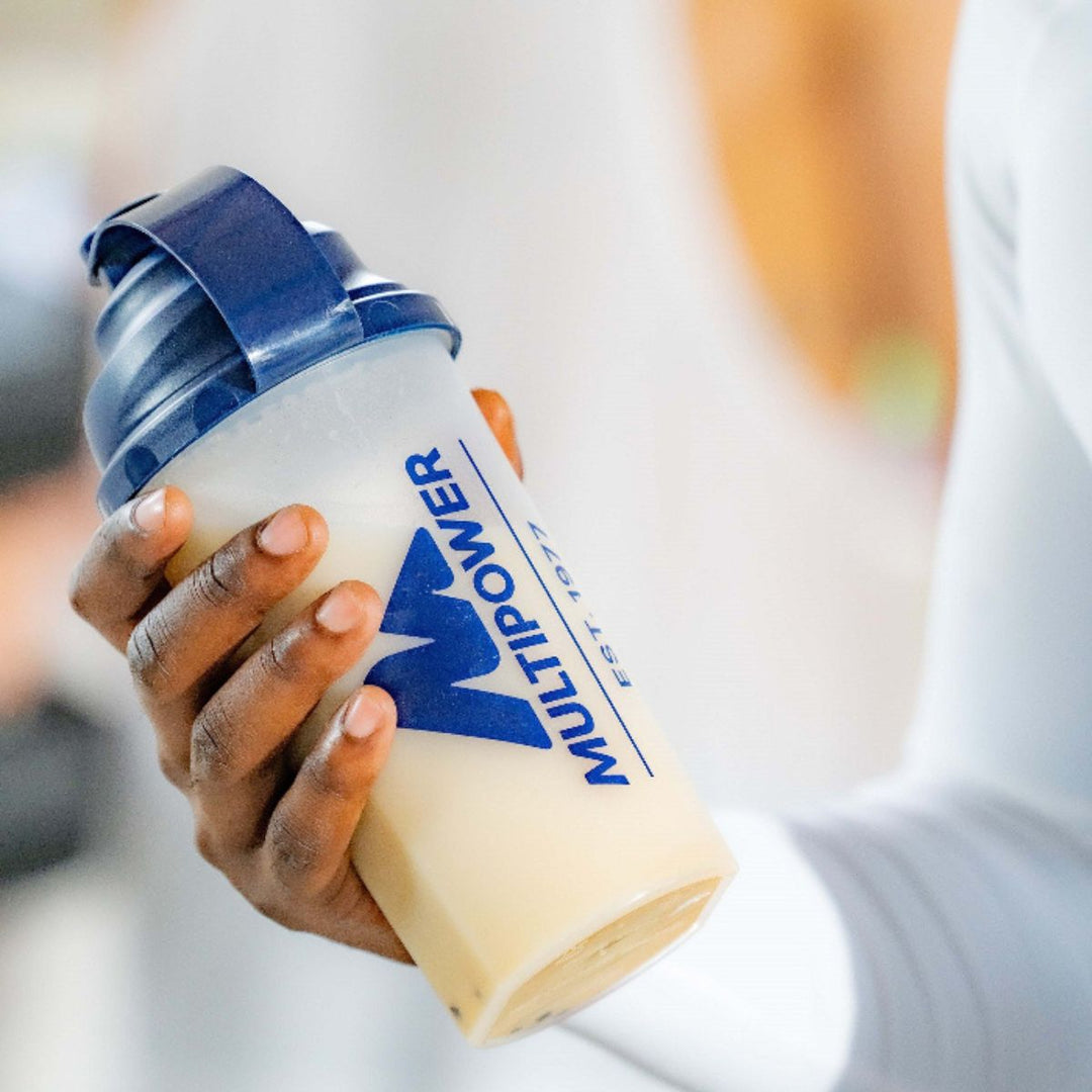 Multipower Proteinshaker - transparenter Shaker mit blauem Deckel, gefüllt mit einem cremigen Proteinshake.