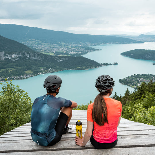 Ein Paar genießt den Ausblick nach der Radtour mit Isostar Flasche