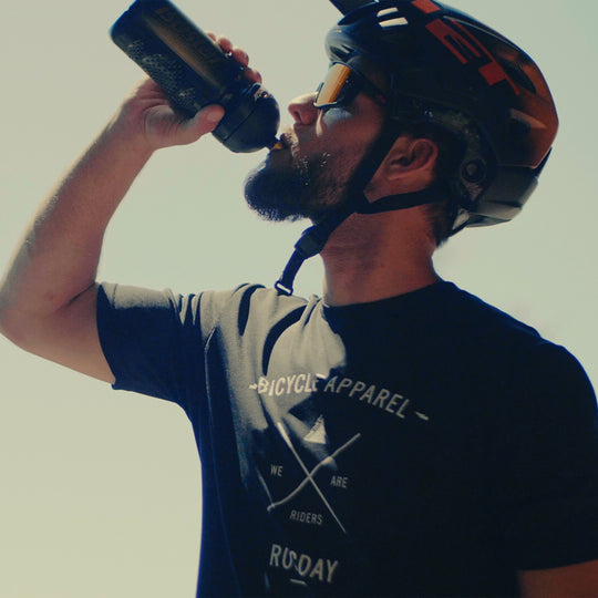 Mann mit Fahrradhelm trinkt aus Isostar Flasche
