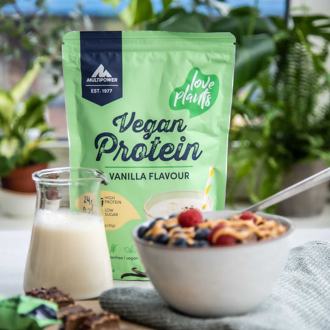 Multipower veganes Proteinpulver im grünen Beutel und davor eine Schüssel Müsli und eine Kanne Milch