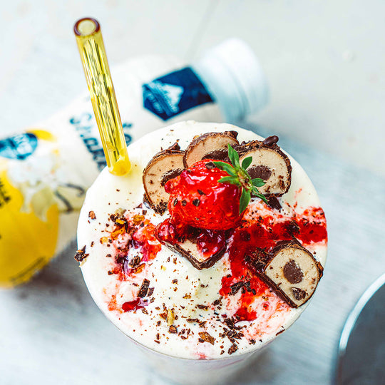 Multipower Vanille Shake in einem Glas mit Riegelstücken und Erdbeeren